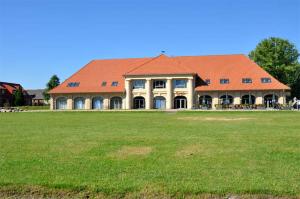a large building with an orange roof on a field at Ferienhaus Stolpe USE 1860 in Stolpe auf Usedom