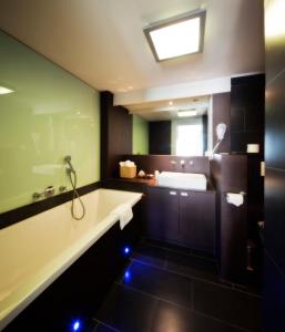 a bathroom with a tub and a sink and a mirror at Van der Valk Hotel Drongen in Drongen