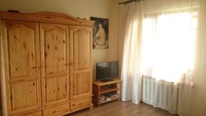 ein Wohnzimmer mit einem TV und einem Holzschrank in der Unterkunft Mētrini apartment near river Daugava in Ķekava