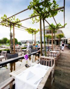 a restaurant with tables and chairs and trees at Van der Valk Hotel Drongen in Drongen