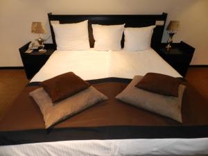 a bedroom with a large bed with two pillows on it at Van der Valk Hotel Drongen in Drongen