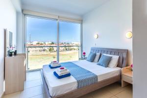 Un dormitorio con una cama y una ventana grande. en Coralli Spa By Fig tree Bay, en Protaras 49 fotos más