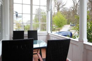 a porch with chairs and a glass table in front of a window at Villa Wilhelmshöhe by Rujana in Binz