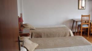a room with two beds and a table and a table at Pension Santa Rita in Santiago de Compostela