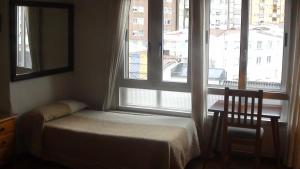 a bedroom with a bed and a window and a chair at Pension Santa Rita in Santiago de Compostela