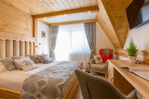 een slaapkamer met een bed en een bureau met een televisie bij Willa Góralsko Riwiera in Zakopane