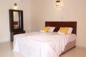 a bedroom with a large bed with white sheets and yellow pillows at Serene Beach Hotel in Dickwella