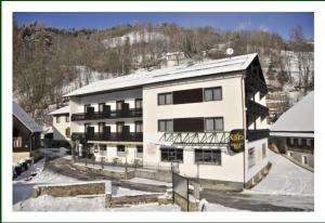 ein großes weißes Gebäude mit Schnee auf dem Boden in der Unterkunft Gasthof-Pension Ortner in Stadl an der Mur