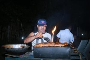 a man is cooking food on a grill at Serene Beach Hotel in Dickwella