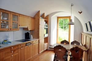 une cuisine avec des placards en bois, une table et une fenêtre dans l'établissement Chasa Schucany, à Ftan