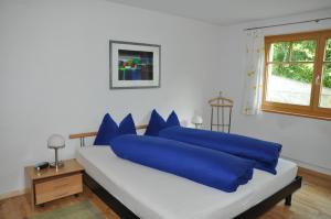 ein weißes Bett mit blauen Kissen im Schlafzimmer in der Unterkunft Trü-Sura Nr. 4 in Scuol