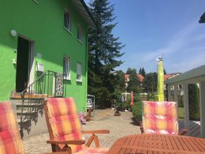 um pátio com uma mesa e cadeiras em frente a um edifício verde em Lamai's Pension em Konstanz