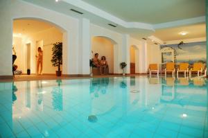 a swimming pool with people standing around in a building at Hotel Eder in Ramsau im Zillertal