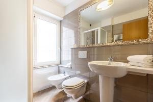 a bathroom with a sink and a toilet and a mirror at Hotel Calypso in Ventimiglia