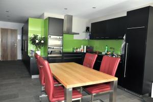a kitchen with a wooden table and red chairs at Chasa Miramunt 7 in Scuol