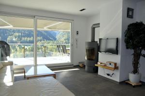 a living room with a tv and a large window at Chasa Miramunt 7 in Scuol +9 photos