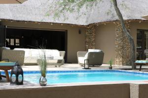 a swimming pool with chairs and a couch in a yard at Luvivane Luxury Villa in Marloth Park