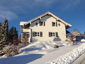 ein weißes Haus mit Schnee auf dem Boden in der Unterkunft Ferienwohnung Unglert in Wertach