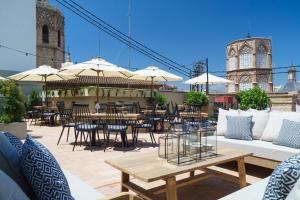 un patio al aire libre con mesas, sillas y sombrillas en The Valentia Cabillers en Valencia