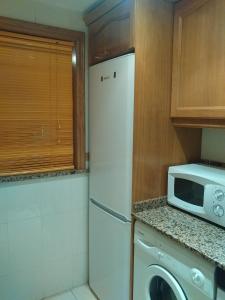 een keuken met een witte koelkast en een magnetron bij Acapulco II, 1a LINEA, Playa Amplaries in Oropesa del Mar