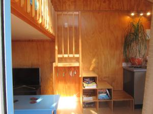 a living room with a book shelf and a staircase at Snowberry Cottage at Lochsloy Farm Little River in Little River +17 photos