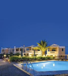 a swimming pool in front of a resort at night at Sun Village Hotel Apartments in Megás Limniónas