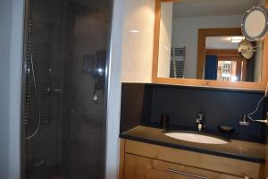 a bathroom with a sink and a shower with a mirror at Eclat de Soleil 023 in Verbier