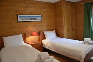 Habitación con 2 camas individuales y paredes de madera. en Eclat de Soleil 023 en Verbier