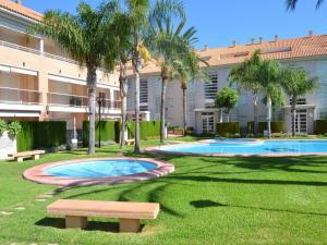 a park with two pools and a bench in front of a building at Apartamento Golden Gardens in Jávea