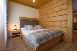 een slaapkamer met een bed met een houten muur bij Willa Góralsko Riwiera in Zakopane