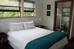 a bedroom with a white bed and two windows at Nkutu River Lodge in Kloof