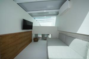 a living room with a white couch and a tv at Pnoe in Mýkonos City
