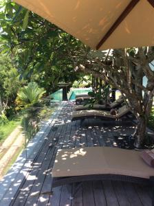 a deck with benches and a tree and a pool at The Puncak Lombok in Senggigi