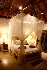 um quarto com uma cama de dossel e cortinas brancas em Luvivane Luxury Villa & Cottage em Marloth Park
