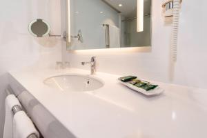 a white sink sitting under a mirror next to a toilet at Spring Hotel Vulcano in Playa de las Americas