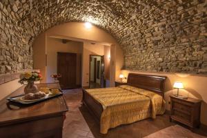 1 dormitorio con cama y pared de piedra en Agriturismo Le Gallozzole en Monteriggioni