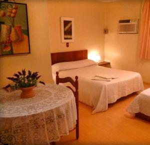 a hotel room with two beds and a table at Hotel Primavera in Bento Gonçalves