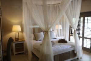 a bedroom with a canopy bed with white curtains at Luvivane Luxury Villa in Marloth Park +27 photos
