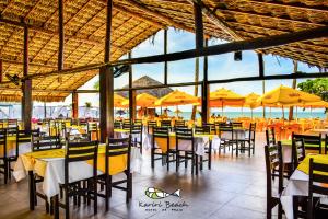 a restaurant with tables and chairs with yellow umbrellas at Kariri Beach Hotel in Cumbuco