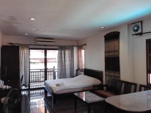 a bedroom with a bed and a table and a balcony at FAA Apartment in Vientiane