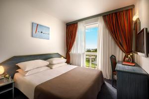 a hotel room with a bed and a window at Aminess Laguna Hotel in Novigrad Istria