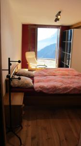 ein Schlafzimmer mit einem Bett, einem Stuhl und einem Fenster in der Unterkunft Appartment Emosson in Finhaut