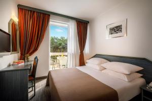 ein Schlafzimmer mit einem Bett, einem Schreibtisch und einem Fenster in der Unterkunft Laguna Maradiso Hotel by Aminess in Novigrad Istria