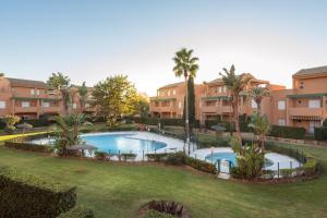 an apartment complex with a large swimming pool with palm trees at Apartamento Mijares in Chiclana de la Frontera