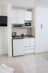 cocina con armarios blancos y microondas en Torre Potosi Departamentos en Rosario