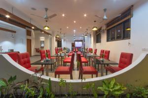 a restaurant with red chairs and tables in a room at Paguro Beach Inn in Ukulhas