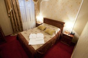 a bedroom with a bed with two white towels on it at Deluxe Hotel Kupava in Lviv