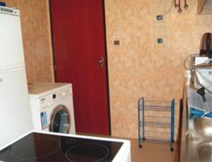a kitchen with a washing machine and a red door at Résidences La Fourmi in Lomé