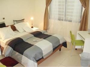 a bedroom with a large bed and a desk at Résidences La Fourmi in Lomé