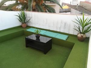 a bench with a table and two plants on a balcony at Apartamentos Andrada in Casar de Cáceres